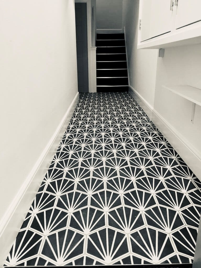 black and white patented tiled floor leading to a white wall black step staircase