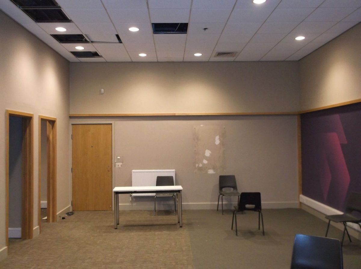 well-lit meeting room with carpeted floor, wooden doors, and velvet abstract side wall design