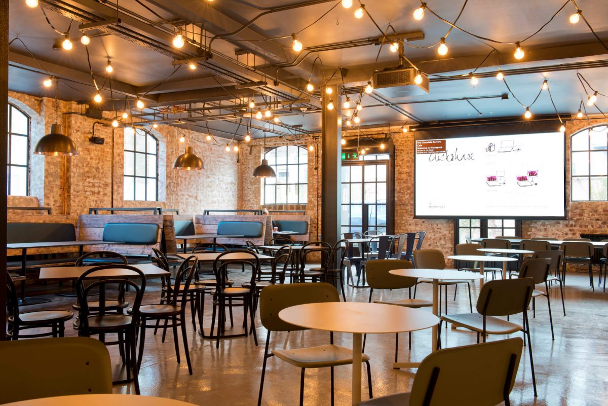chocolate factory dining table with round tables on the side and a projector