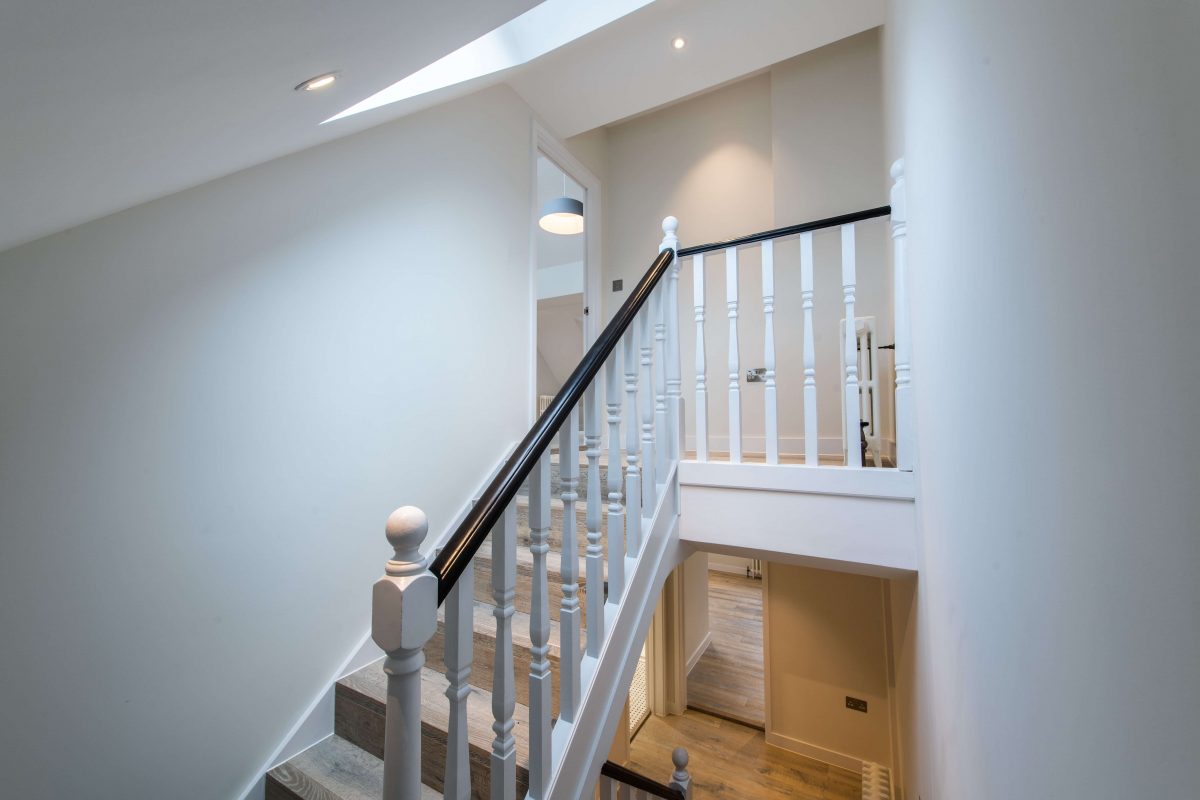 slanted ceiling stairwell with bright sky light and well lit landing
