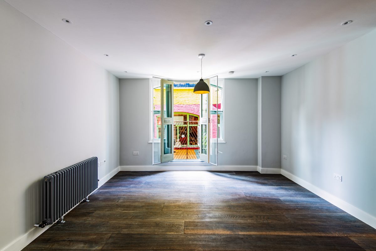 light modern room with black radiator and dark wood flooring