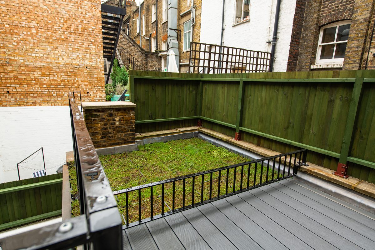 backyard, dark green fence and grey wooden flooring