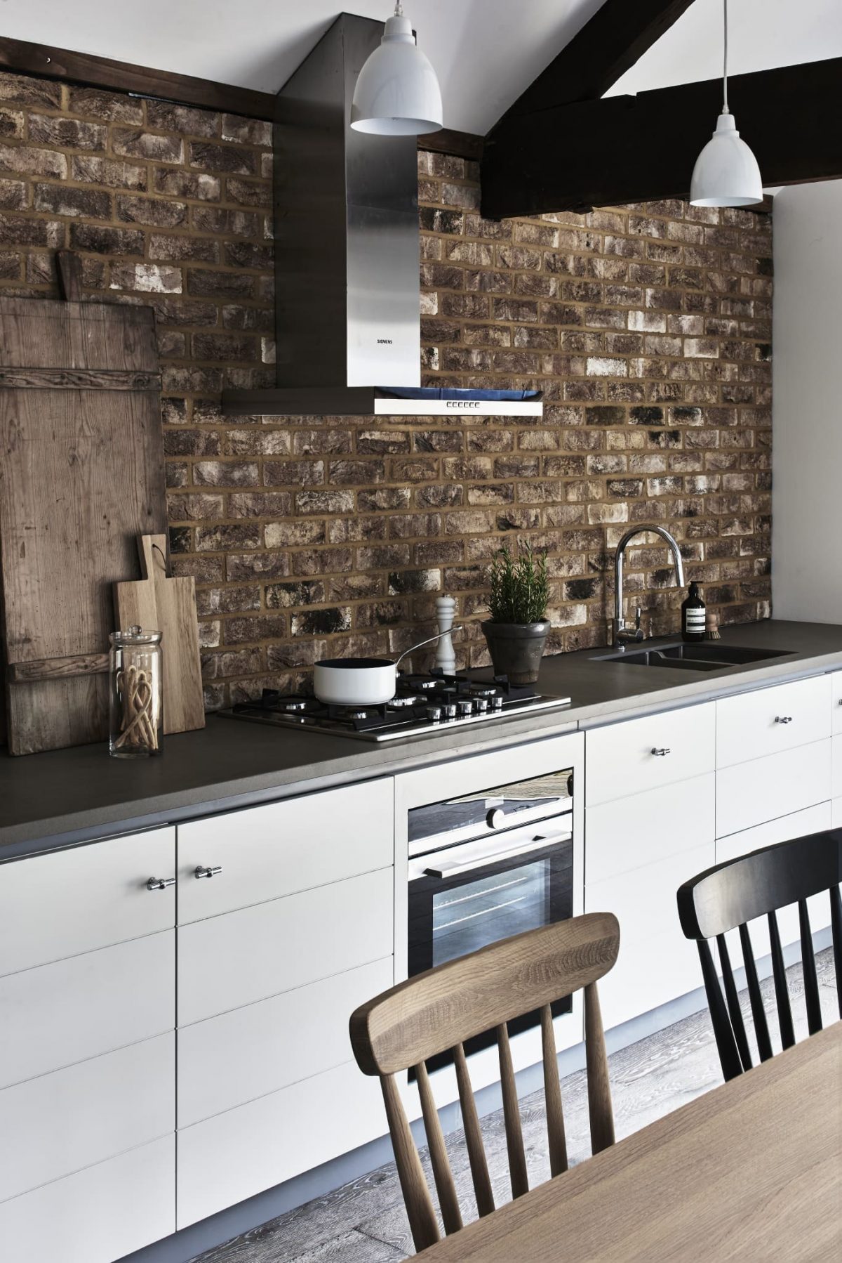 white kitchen cabinets with modern black counter top set against a bear brick wall